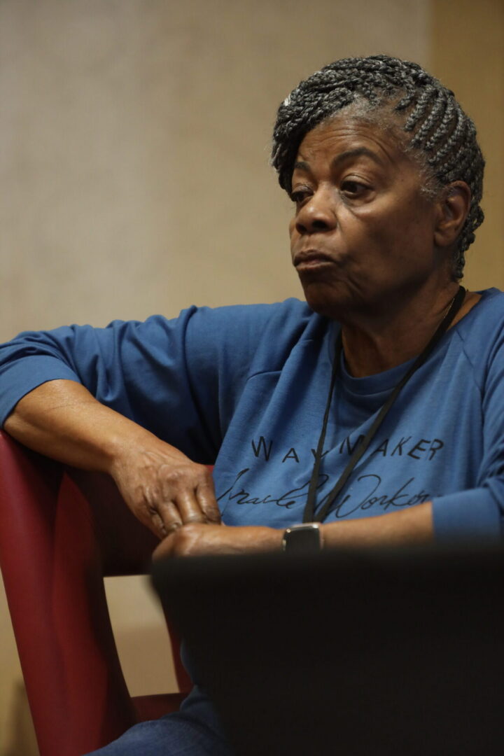 Woman sitting thoughtfully in a blue shirt.